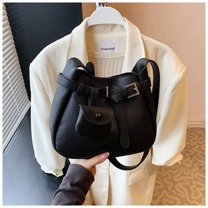 Detail of black lychee grain leather handbag with metal buckle and mini attachment