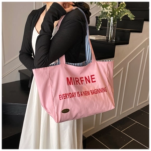 Pink canvas tote bag featuring red letters and blue-white striped lining details