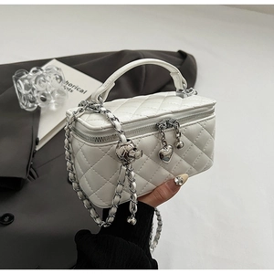 Detailed close-up of a white quilted vanity bag with elegant silver heart charms