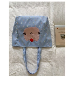 Détail du sac cabas à carreaux bleus avec broderie chat rose sur un tissu blanc