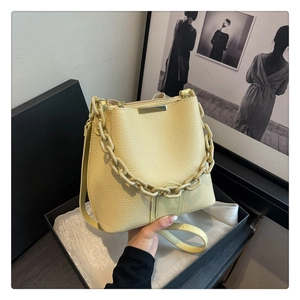 Détail du sac seau en cuir jaune avec chaîne épaisse et garniture métallique dorée