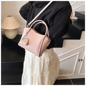 Detail of pink pebbled leather bucket bag with silver hardware and adjustable strap