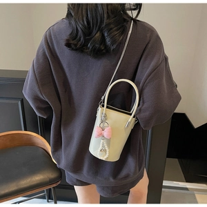 Detail der cremefarbenen Beuteltasche mit rosa Schleife und Perlenanhänger