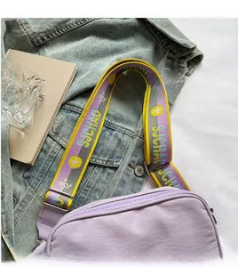 Detail of purple canvas camera bag featuring a wide embroidered striped shoulder strap
