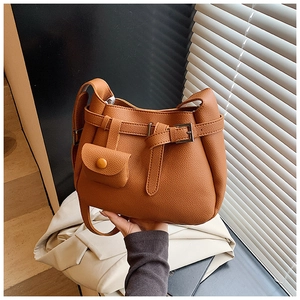 Detail view of brown lychee grain leather bucket bag with decorative buckle and mini pouch