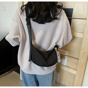 Model wearing a black crescent nylon crossbody bag with an adjustable wide shoulder strap