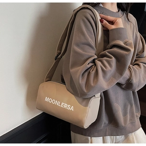 Detailed street style view of beige cylinder canvas bag with wide adjustable shoulder strap