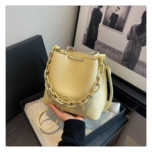 Détails de la texture litchi et de la chaîne mate sur le sac seau de couleur jaune pâle