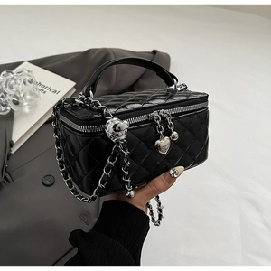 Detail of black quilted chain bag with silver heart charm and adjustable metal ball buckle