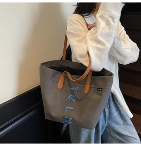 Mannequin portant un grand sac cabas en toile grise avec anses en cuir brun et broderies