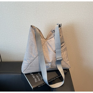 Detail of light grey casual crossbody bag with woven fabric texture and white label
