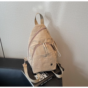 Detail of khaki nylon backpack featuring white elastic pullers and functional compartments