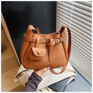 Detail of caramel brown litchi textured leather shoulder bag with a mini pouch charm