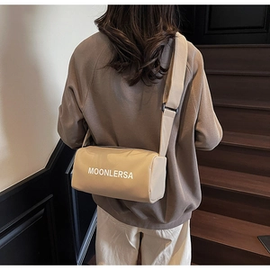 Rear view of khaki nylon barrel crossbody bag with wide strap worn by a model