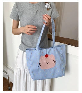 Détail du sac cabas en toile à carreaux bleu clair avec patch chat rose et poignée