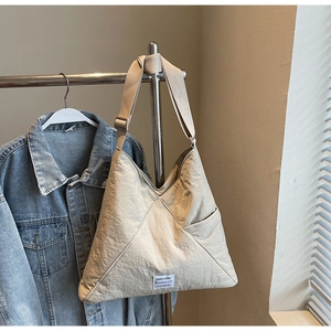 Detail of a large beige nylon hobo bag with adjustable strap and casual white label tag