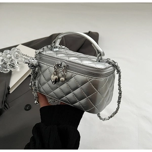 Detailed close-up of a silver quilted mini vanity bag with a heart-shaped metal pendant