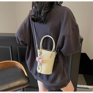 Details der cremefarbenen Beuteltasche mit rosa Karoschleife und Perlenanhänger
