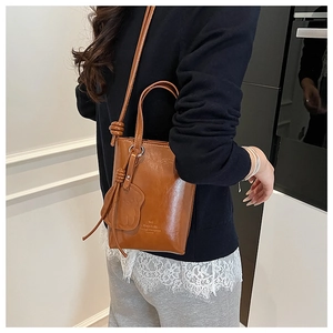 Detail view of brown PU leather bucket bag with cute bear charm and FANTON logo