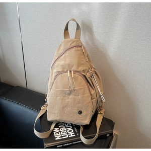 Close-up of khaki nylon chest bag with wrinkled texture and zipper pocket details