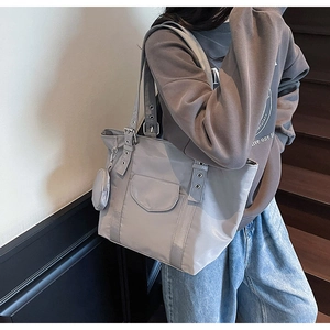 Grey nylon tote bag with small round pouch and grommet strap shown on model on stairs
