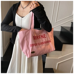 Pink canvas tote bag with red letter print shown on model shoulder for daily commute