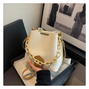 Détail du sac seau blanc cassé avec chaîne épaisse et bandoulière en cuir grainé