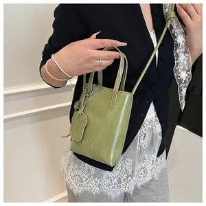 Close-up of green mini tote bag with leather bear charm and brand embossed detail