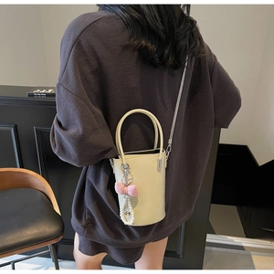 Detailansicht beige Mini-Eimertasche mit Perlen-Schleife und Metall-Kettenriemen