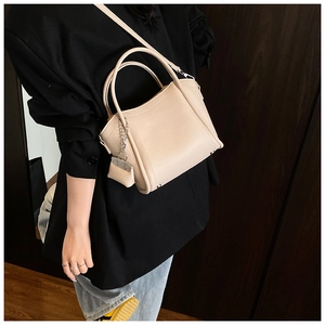 Detail showing the lychee grain leather texture and a matching mini pouch charm on the bag
