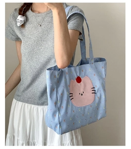 Détail du sac cabas à carreaux bleus et blancs avec patch chat rose et détails rouges