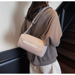 Detail of light pink cylindrical crossbody bag with wide strap worn by a model