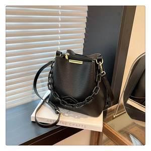 Détail du sac seau en cuir grainé noir avec chaîne épaisse et finitions dorées