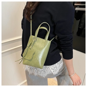 Close-up of matcha green mini bucket bag with bear pendant and crossbody strap detail