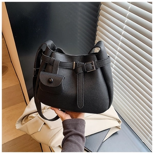 Detail of black pebbled leather texture and belt buckle strap on crossbody bag
