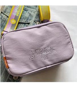 Detail of purple canvas camera bag with white letter embroidery and colorful strap