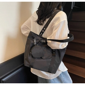 Detail of black nylon tote bag with metal rivet strap and matching round coin purse pouch
