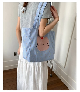 Gros plan du sac cabas en toile à carreaux bleus avec écusson de chat rose mignon