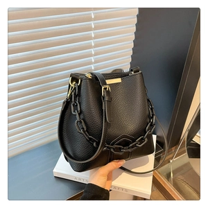 Vue détaillée du sac seau en cuir grainé noir avec chaîne épaisse et fermoir métallique