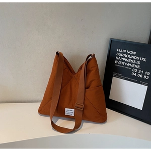 Detail of caramel puffer shoulder bag with KEEP GOING label and adjustable strap