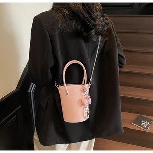 Rosa Eimertasche mit Silberkette und Herzanhänger an Model im schwarzen Anzug