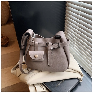 Detail of taupe pebbled leather bucket bag with belt buckle and small pouch