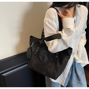 Detail of black nylon cargo tote bag featuring heart pocket and mini round pendant