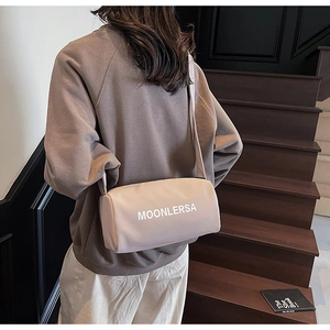 Lifestyle shot of beige cylinder canvas crossbody bag with wide strap on a model