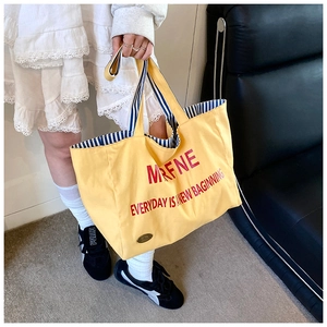 Detail of yellow canvas tote bag featuring red typography and striped fabric lining