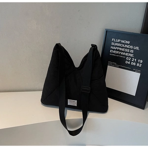 Detail of minimalist black canvas tote bag with adjustable strap and woven brand label
