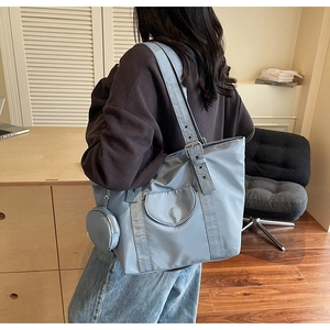 Detail view of large blue tote bag with adjustable grommet strap and small coin purse