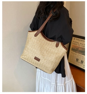 Détail d'un grand sac cabas en paille avec anses en cuir porté par un mannequin