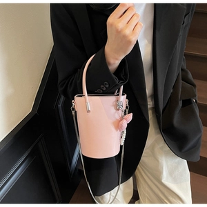 Rosa Lederbeuteltasche mit Schleifenanhänger und Kettenriemen auf schwarzem Blazer
