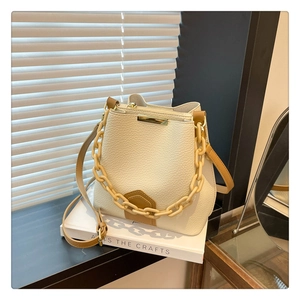 Détail du sac seau blanc crème avec texture litchi et poignée à grosse chaîne